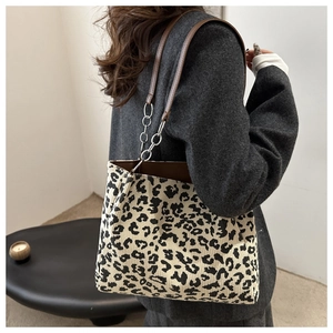 Close-up of leopard print tote bag with metallic chain and brown leather strap detail