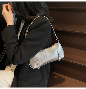Silver metallic shoulder bag with pleated texture worn by a model in a black blazer