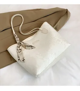 Close-up of white python embossed tote bag with elegant silk scarf on the handle
