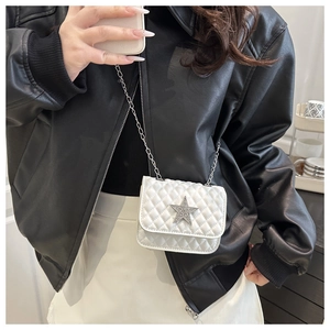 White quilted chain bag with a sparkling star buckle worn over a leather jacket
