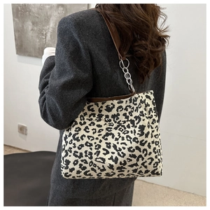 Detail of leopard print corduroy shoulder bag with leather chain strap on a model
