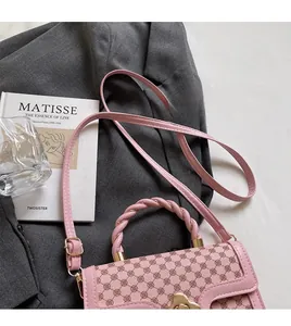 Detail of pink leather handbag featuring a braided handle and wave gold clasp