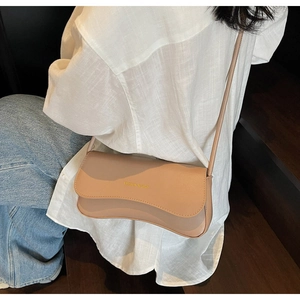 Detail of khaki baguette shoulder bag featuring wave-edge flap and fashion gold lettering