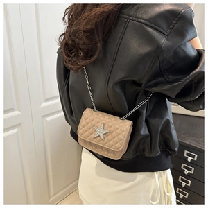 Detail view of a quilted beige crossbody bag with a rhinestone star and silver chain