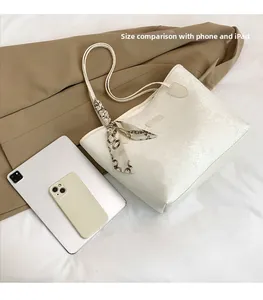 Detail view of large white snake-pattern tote bag showing capacity with tablet and phone