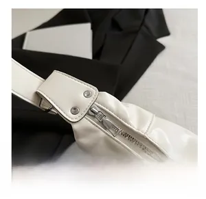 Close-up of glossy white leather bag showing silver metal zipper and buckle details