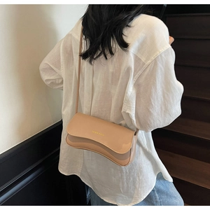 Close-up of beige leather shoulder bag with gold Fashion & Bags logo on model