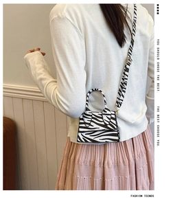 Mini zebra print handbag shown on model featuring round handle and detachable strap