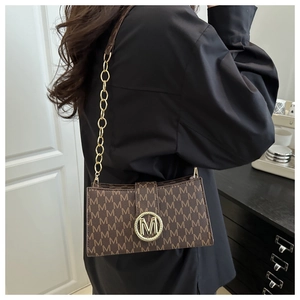 Detail of the monogrammed brown leather shoulder bag with golden M clasp and chain strap