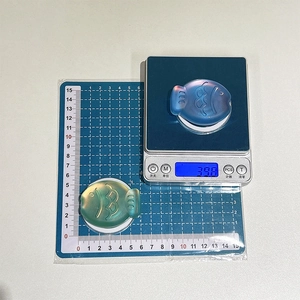 Macro shot showing fish-shaped magnetic phone grip weight and dimensions on blue scale