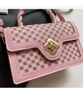 Close-up of pink handbag featuring woven handle and clover pattern with golden floral lock