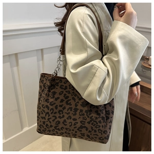 Detail of leopard print tote bag with brown leather straps and silver metal chain decoration
