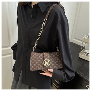 Detailed view of brown monogram handbag with gold M-logo buckle and metal chain strap