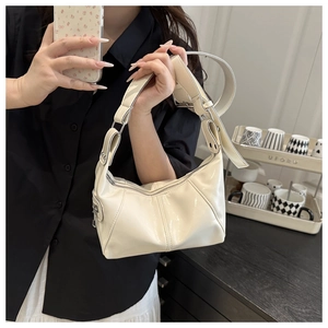 Detail of glossy cream leather shoulder bag with silver hardware and adjustable strap