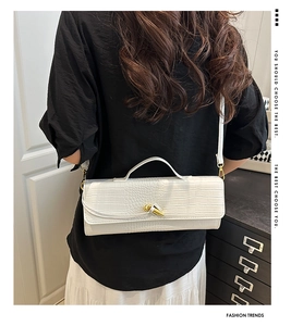 Chic white crocodile pattern handbag with gold twist lock shown styled on a model's shoulder