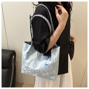 Lifestyle view of a light blue jacquard tote bag with butterfly tassel and woven handle