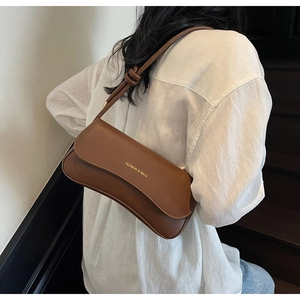 Detail of a brown leather shoulder bag featuring a knotted strap and golden lettering logo