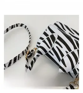 Macro shot of zebra print texture on a crossbody bag with golden metal hardware detail