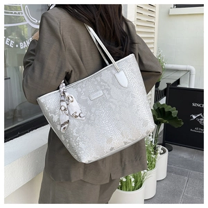 Detail of silver grey snake skin tote bag with decorative silk scarf on shoulder strap