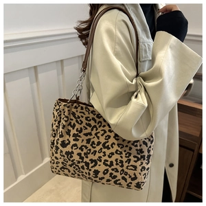 Close-up of leopard print canvas tote bag with brown leather strap and chain detail