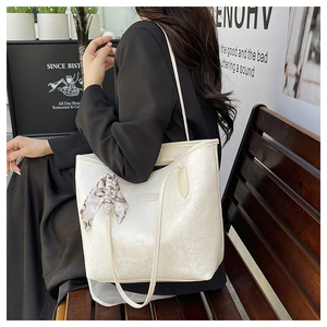 Close-up of white textured leather tote bag with a decorative silk scarf on the strap