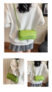 Detail view of bright green baguette bag showing adjustable strap and fashion logo lettering