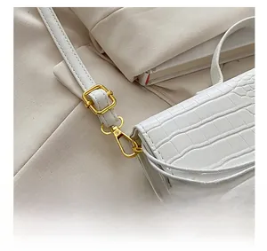 Detailed close-up of golden metal buckle and white crocodile texture leather handbag