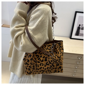 Detailed side view of leopard print tote bag with brown leather and chain straps