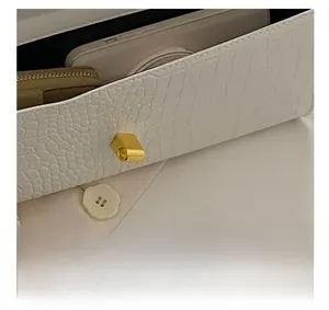 Detail view of white crocodile pattern baguette bag showing magnetic closure and interior