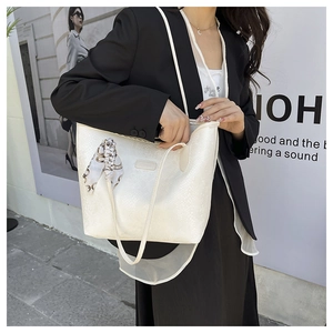 Detail of white snakeskin pattern tote bag with printed silk scarf on urban model