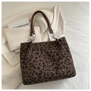 Close-up of leopard print corduroy tote bag with brown faux leather handles and metal rings