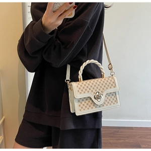 Detail of cream square bag with brown monogram, woven handle and flower metal clasp