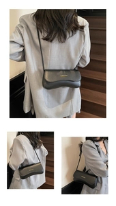Detail of black matte leather shoulder bag featuring gold lettering and adjustable strap