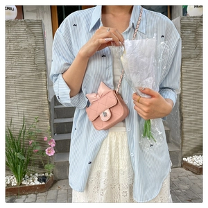 Pink quilted crossbody mini bag with bow detail and silver flower clasp on a female model
