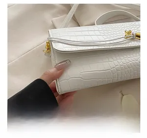 Detailed view of white crocodile pattern shoulder bag with elegant gold twist lock closure