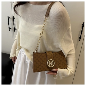 Detail of vintage brown shoulder bag with MK pattern and large metal logo on flap