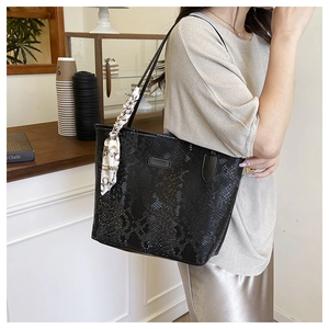 Close-up of black snake-embossed tote bag featuring a chic geometric patterned silk scarf