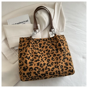 Detail of leopard print tote bag with corduroy texture and brown leather handle strap