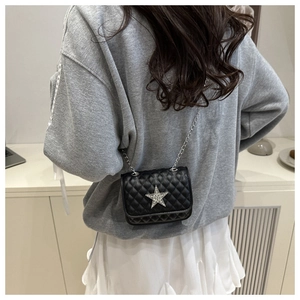 Close-up of a quilted black crossbody bag with a large silver rhinestone star and chain