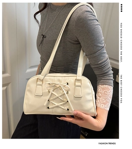 Close-up of cream underarm bag featuring vintage corset style lace-up details