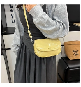 Detailed view of yellow glossy patent leather crossbody bag with adjustable strap