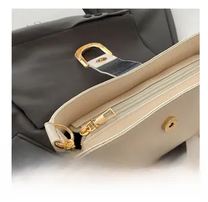 Close-up of cream leather bag showing smooth gold zipper and iconic D-ring buckle detail