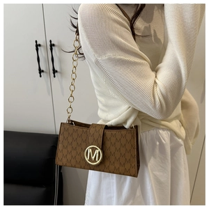 Dettaglio borsa a tracolla marrone vintage con monogramma e fibbia in metallo dorato