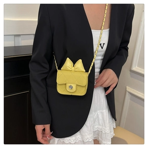 Detail of yellow quilted mini crossbody bag with a bow and metal flower clasp