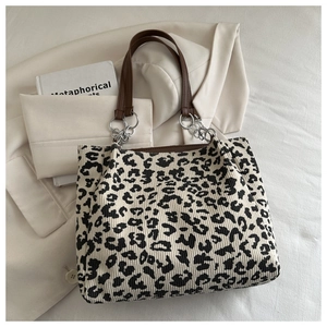Close-up of leopard print tote bag with brown leather strap and metal chain detail