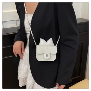 Close-up of white quilted mini bag with bow decoration and camellia flower clasp