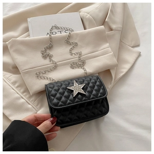 Detail of black quilted crossbody bag featuring a crystal star and silver chain strap