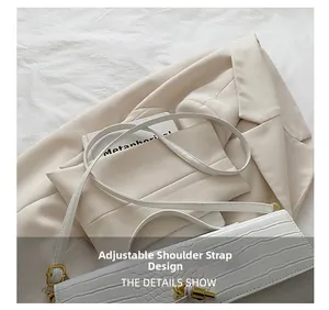Close-up of white crocodile pattern shoulder bag with adjustable strap and gold hardware