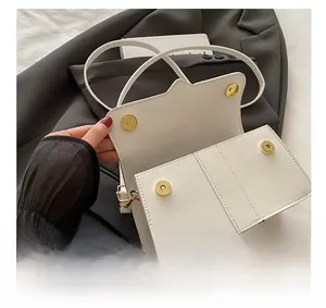 Detailed interior of a white leather crossbody bag with gold magnetic snaps and lining