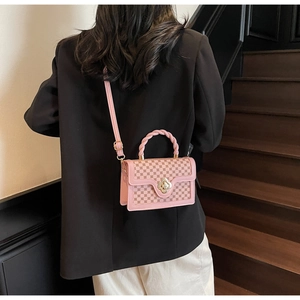 Pink retro checkered crossbody bag with gold floral clasp shown on person’s back